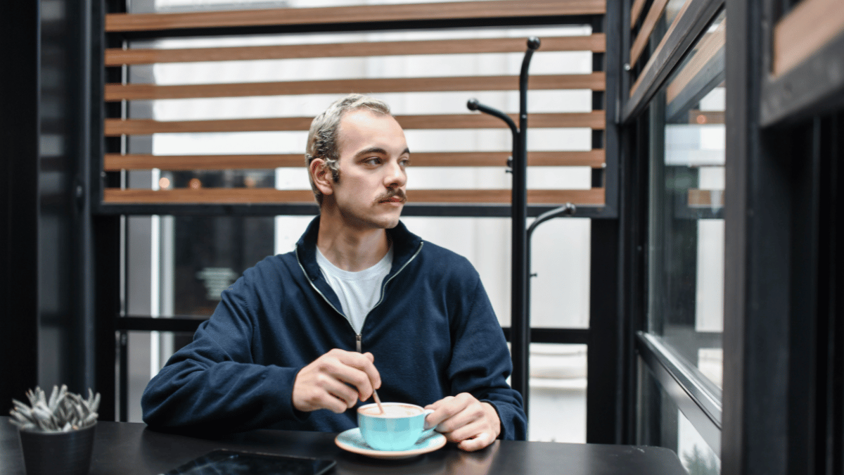 John, a successful entrepreneur, sipping his morning coffee while looking through a window, reflecting on the transformative power of morning routines.