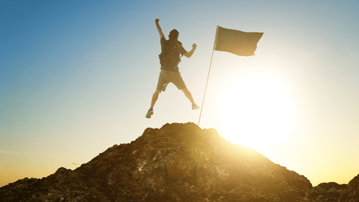 The Entrepreneurial Success A triumphant entrepreneur stands at the peak of a mountain, holding a flag that symbolizes their achievement. The journey to the top has been long and arduous, but the view from the peak is worth every challenge faced. This image embodies the culmination of hard work, persistence, and the consistent application of success habits.